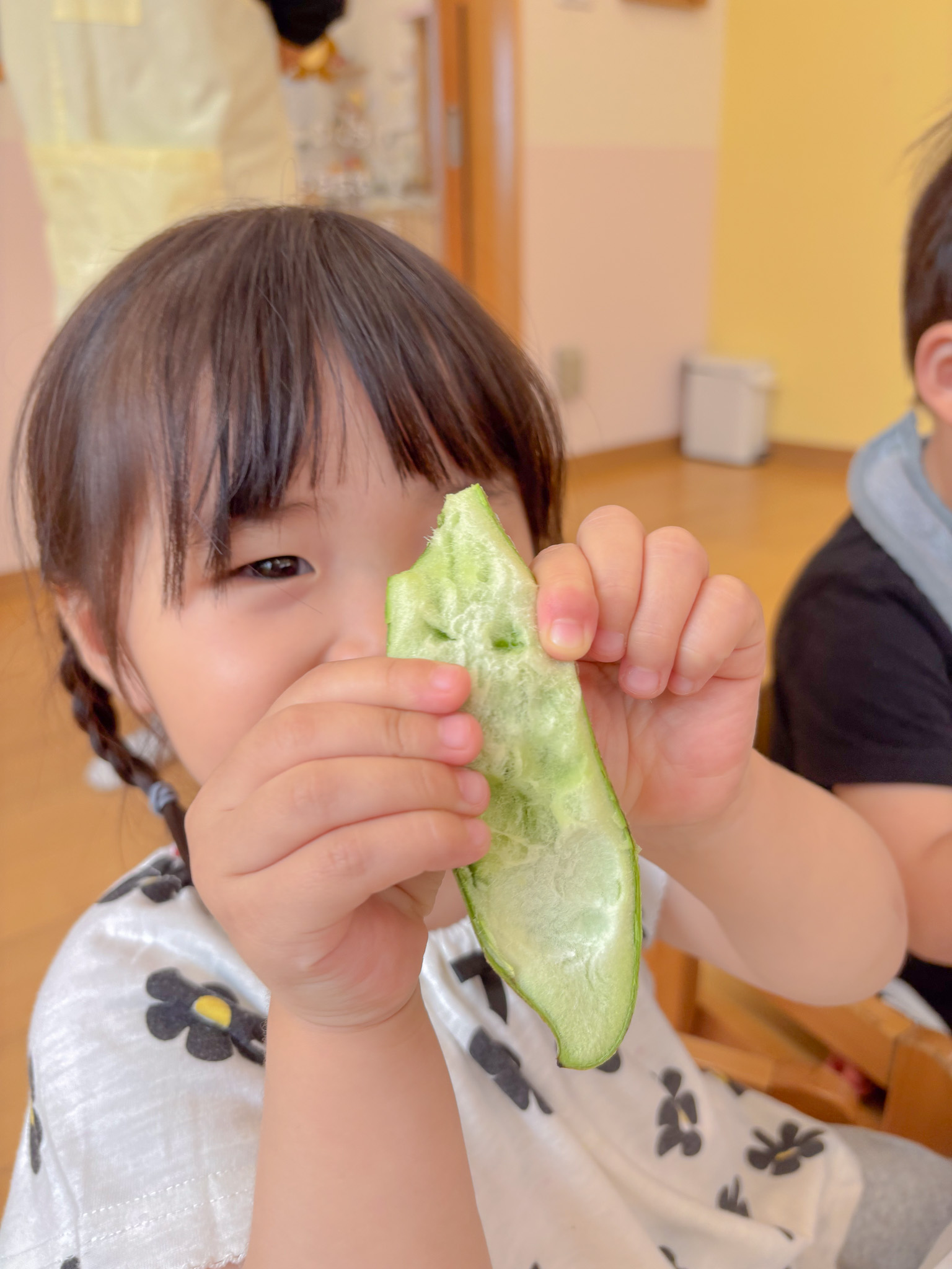そらまめのさやを開いて見せる子