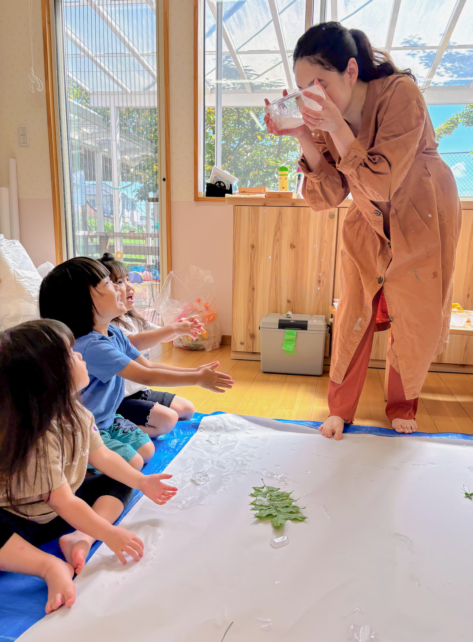 大きな氷をのぞきこむ先生と子どもたち