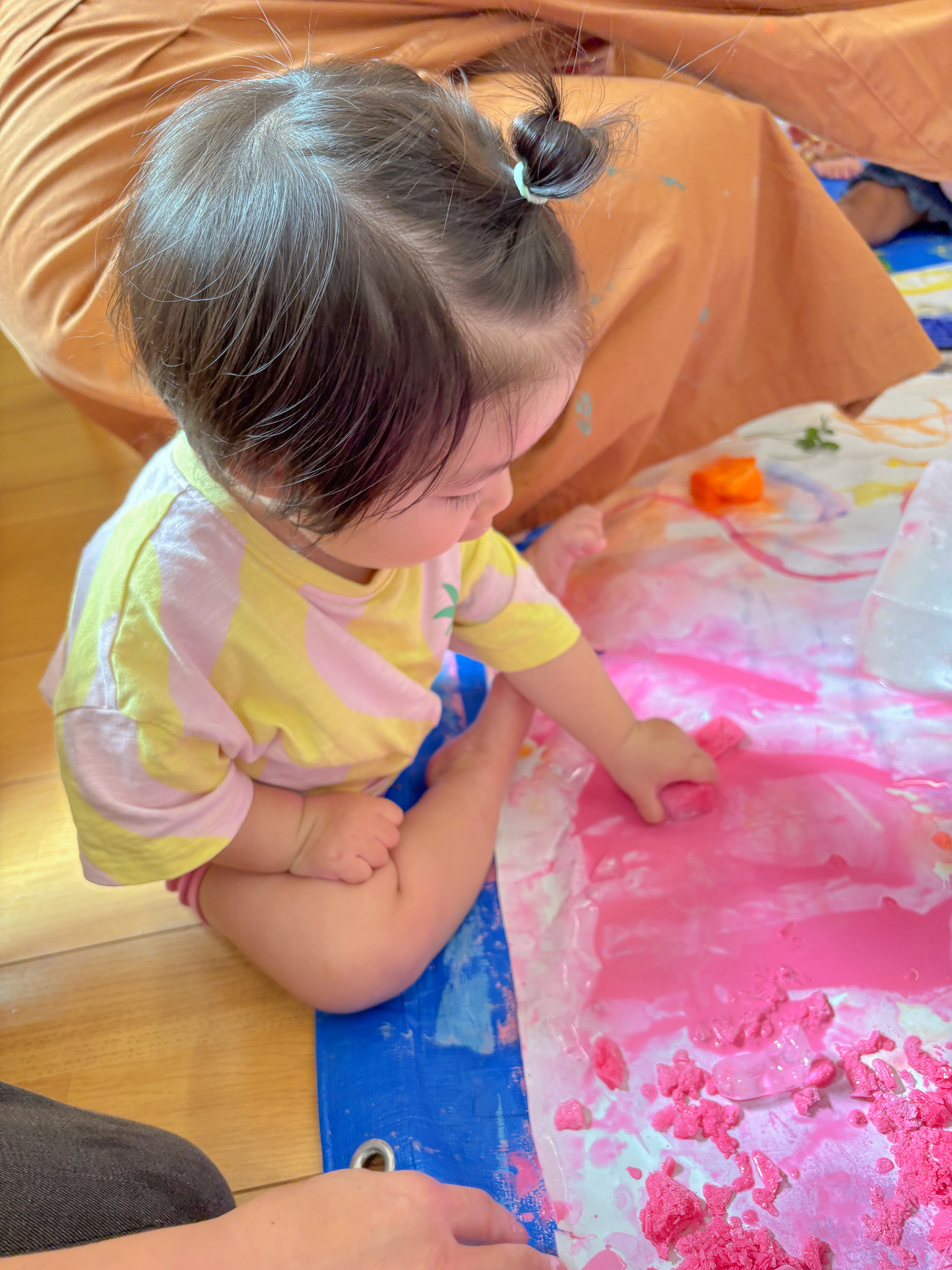 溶けたピンクの氷を触る幼児