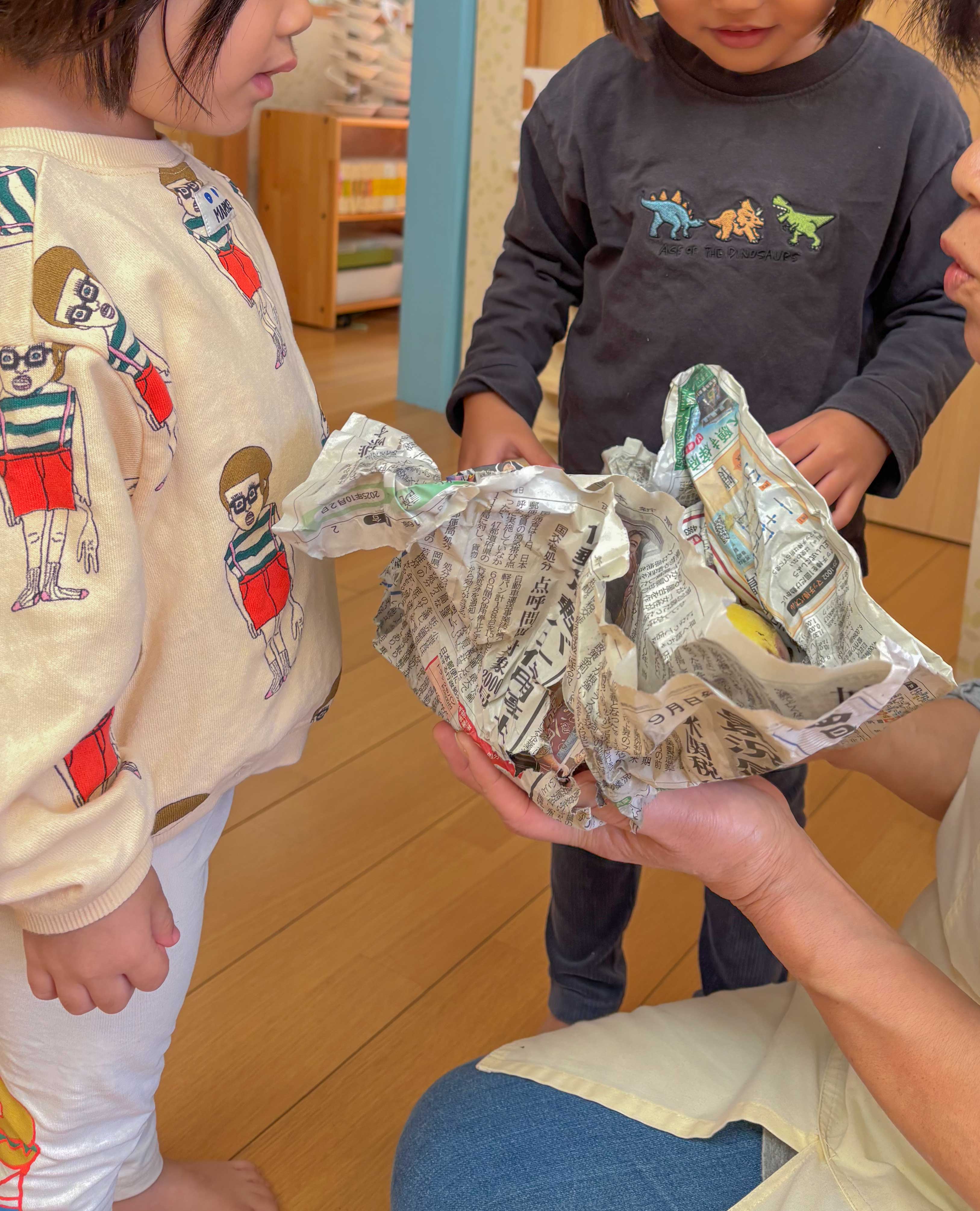 焼きいもを包んだ新聞紙を開く子どもたち