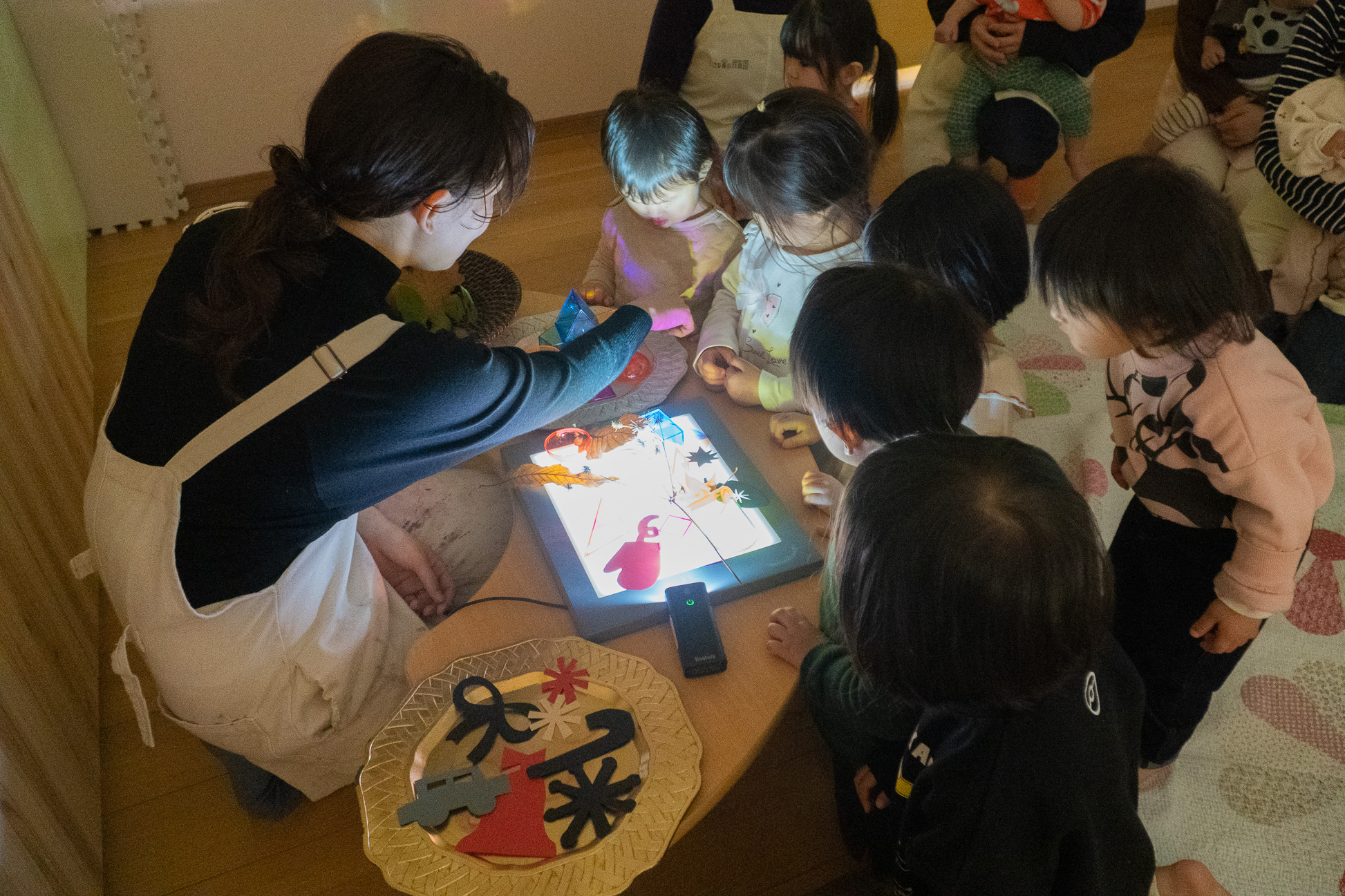 友だちと囲んで光のテーブルを楽しむ子どもたち