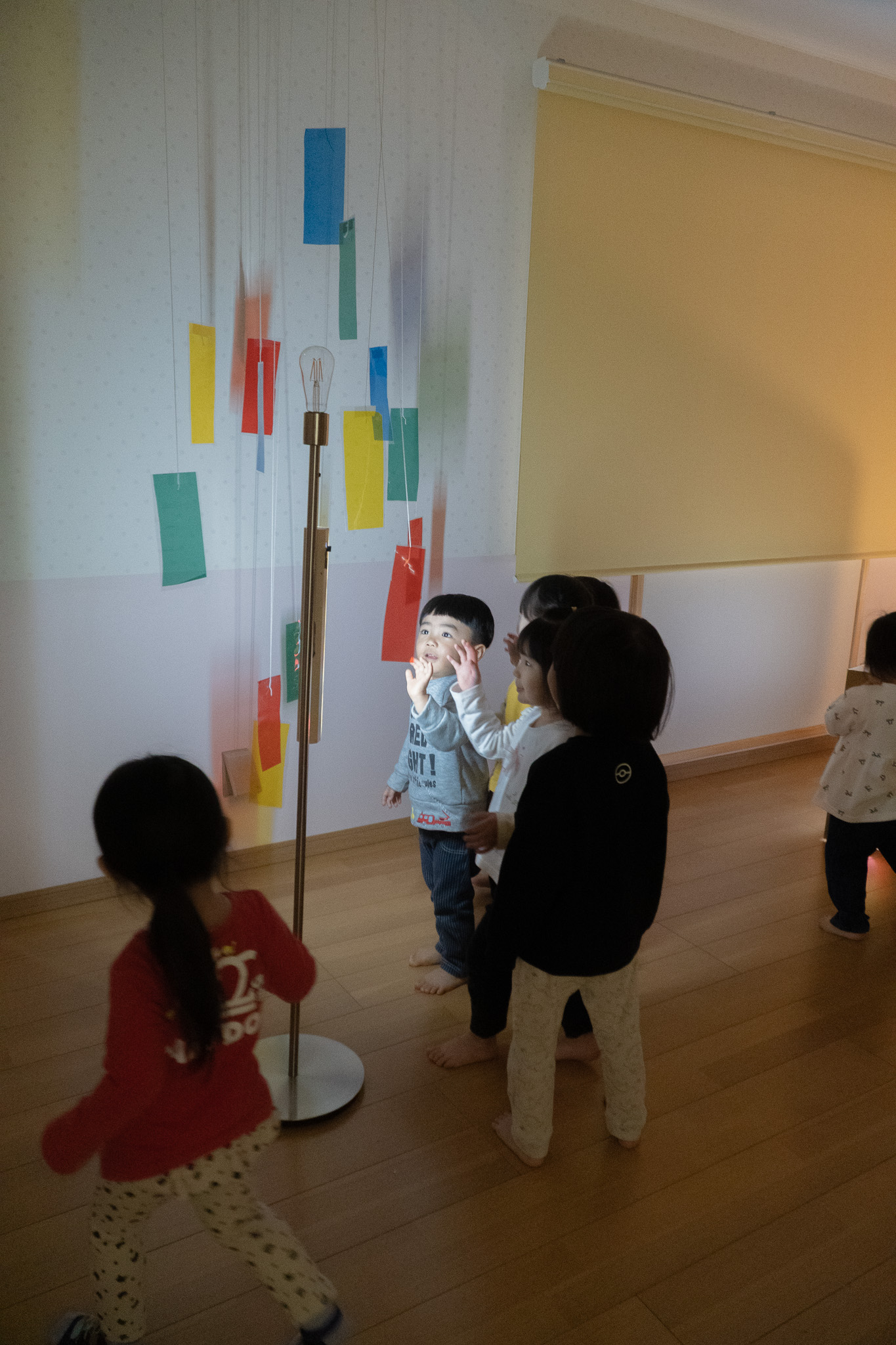 吊るされた色紙と光を見上げる子どもたち