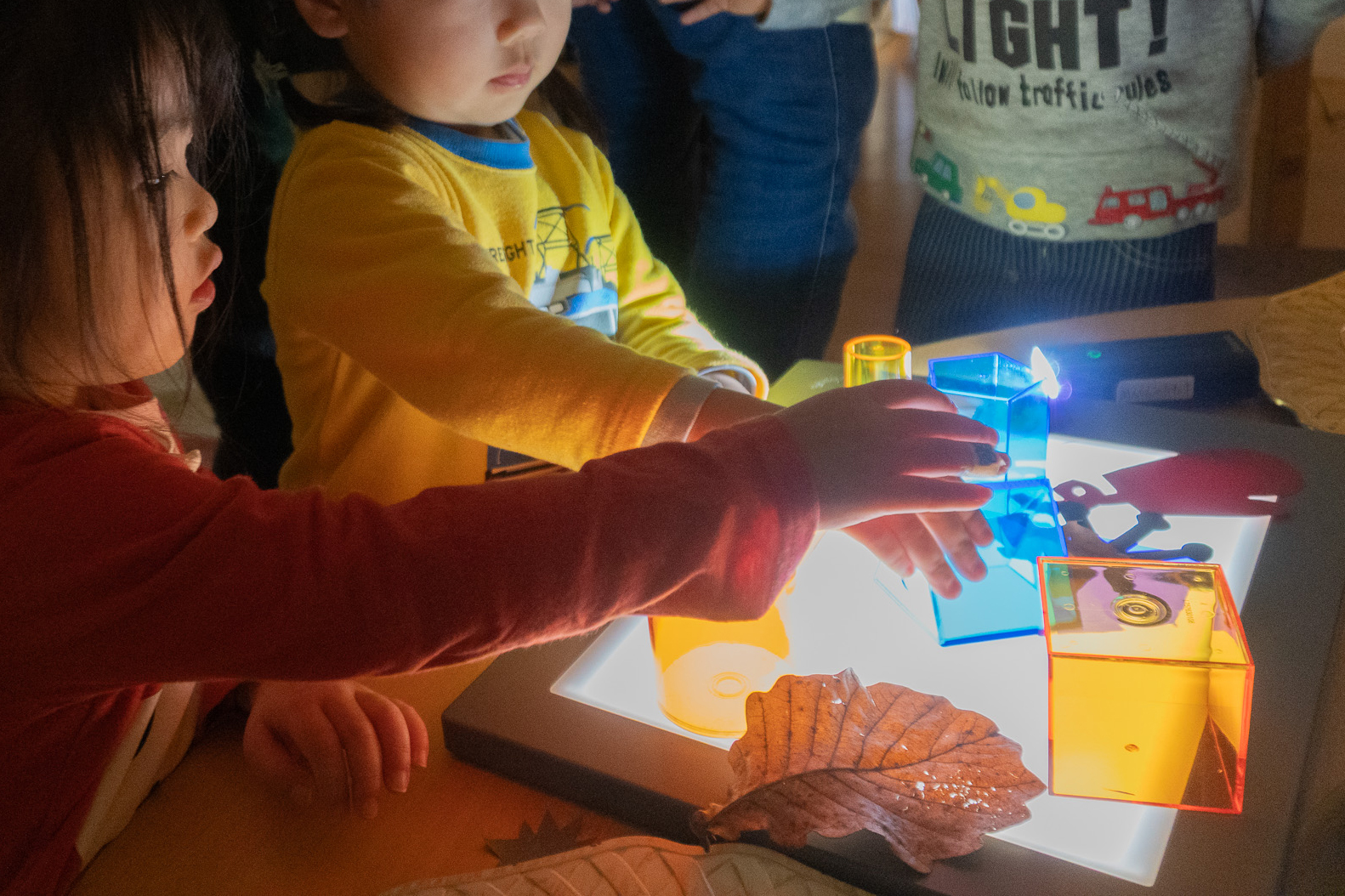 トレース台の上でカラーブロックを動かす子どもの手元