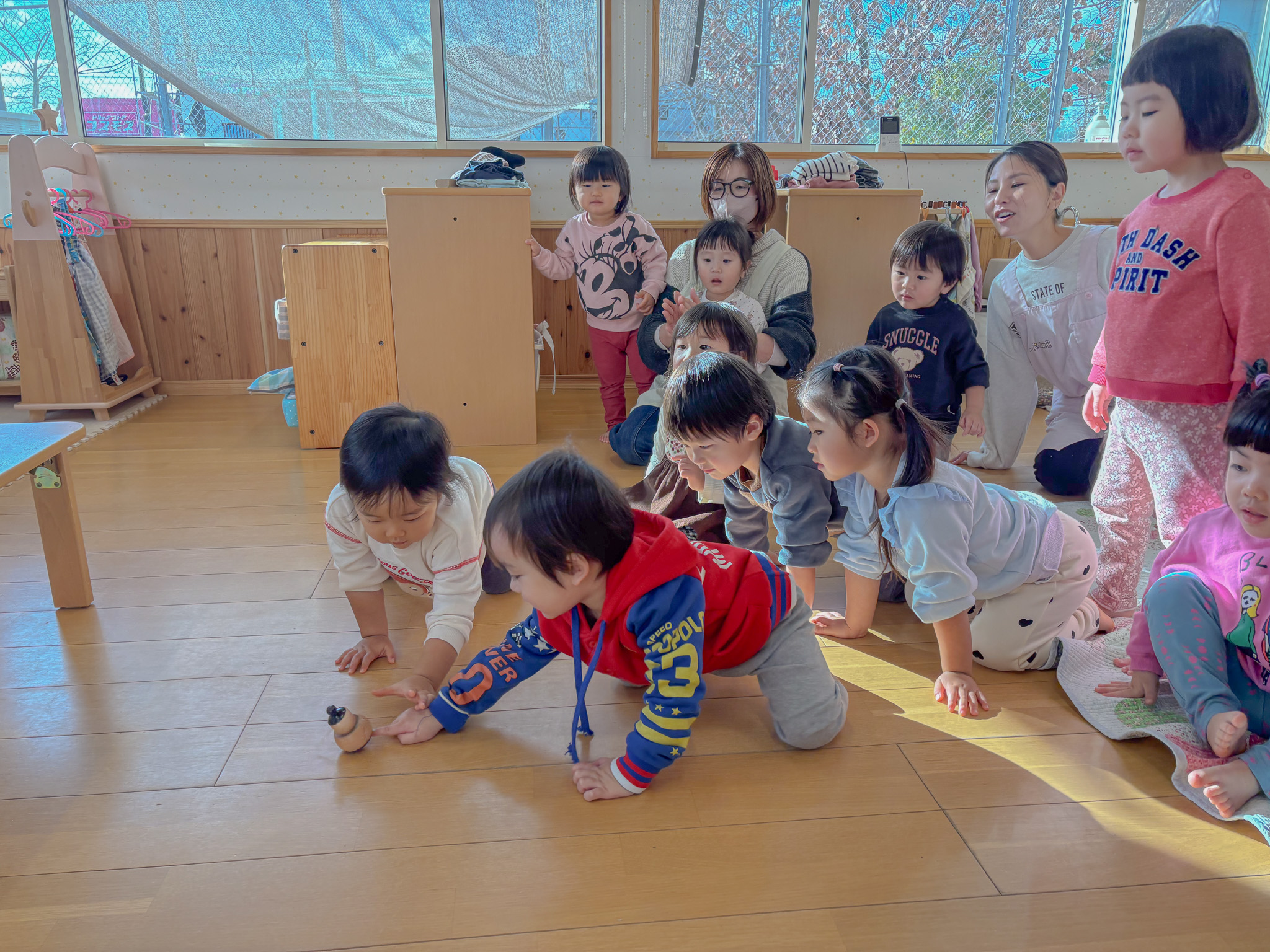 コマで遊ぶ様子を見る子どもたち