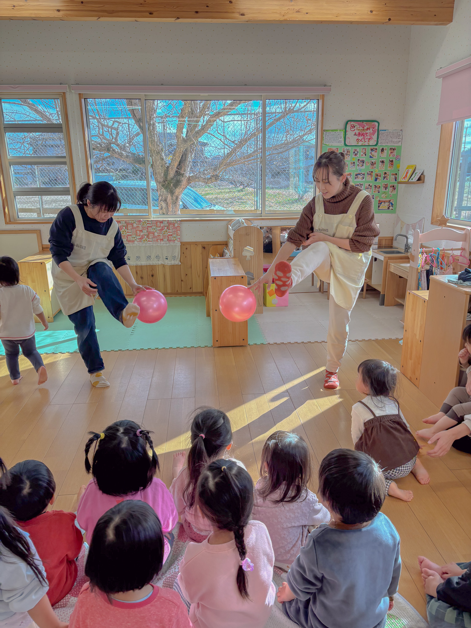 鞠つきをする先生たちと見ている子どもたち