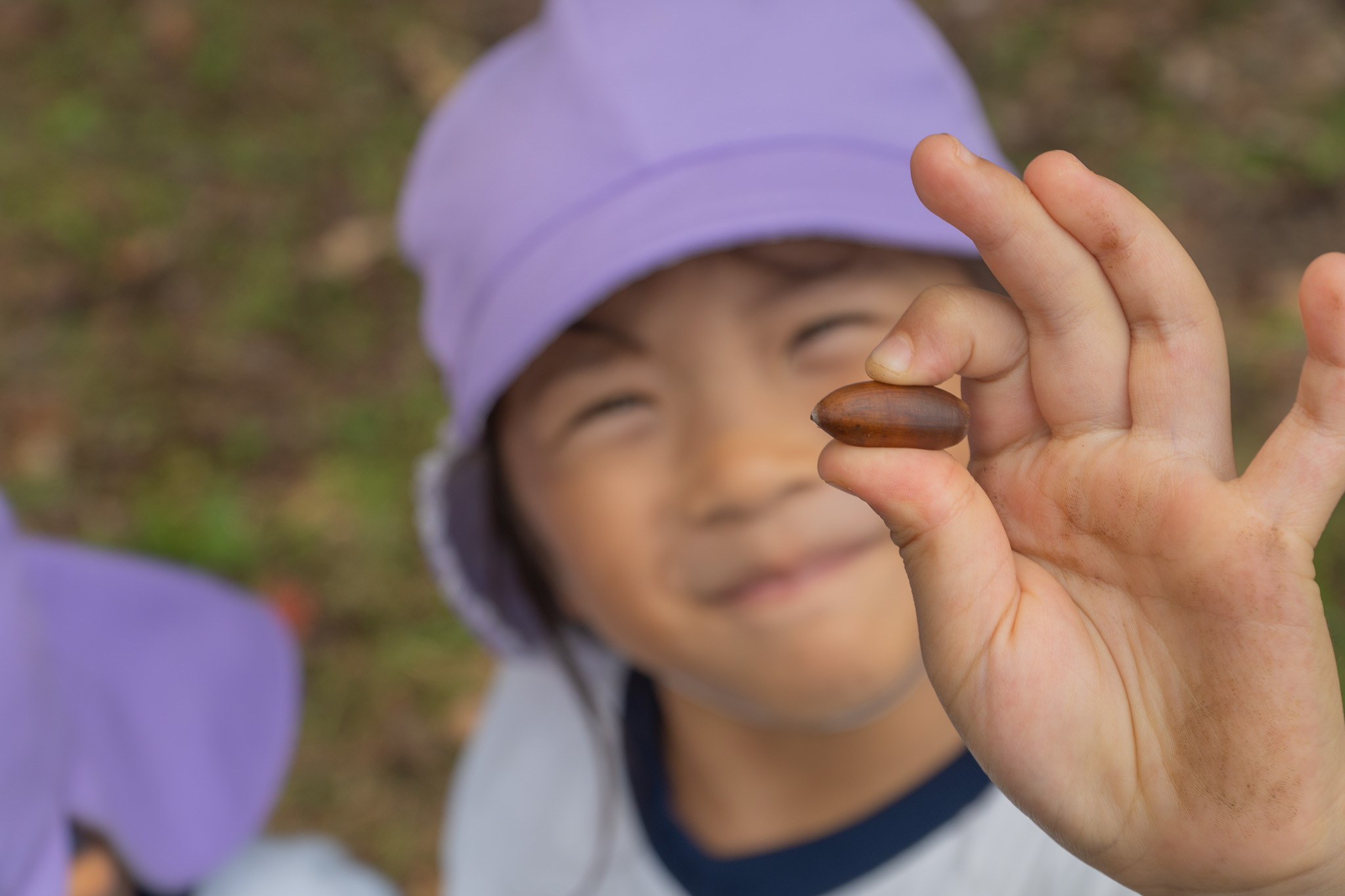 どんぐりを見せる笑顔の子ども